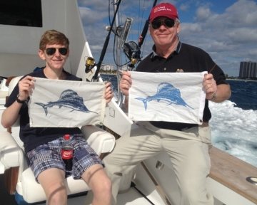 Guy and a kid holding up blue marlin flags